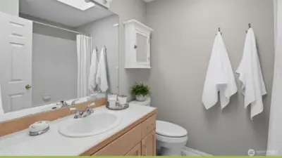 There is a full hall bath with a skylight vinyl flooring and tile counters.