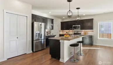 Gourmet kitchen offers a large center island, granite countertops with full-height backsplash, stainless-steel appliances and convenient pantry.