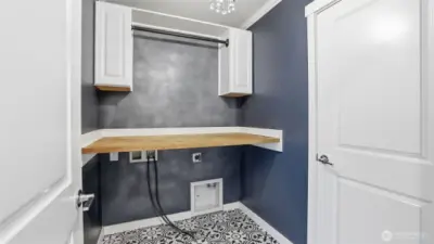 Beautiful laundry room on upper level offers stunning tile flooring, custom shelf over washer/dryer area to maximize space, designer paint and light fixture.