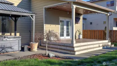 Spacious covered deck with low-maintenance Trex decking and exterior lighting along wedding-cake steps.