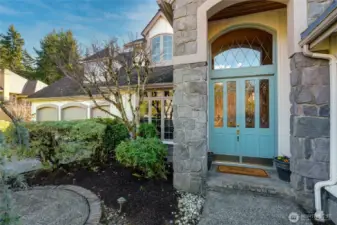 Inviting grand entry with elegant stonework, arched transom, and custom glass double doors.
