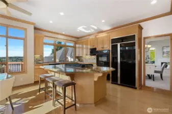 Gourmet kitchen featuring granite countertops, center island with seating and expansive windows showcasing stunning water views, the perfect blend of function and beauty.