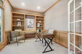 Main-floor home office featuring ample built-in shelving and cabinetry, offering a functional and refined workspace.