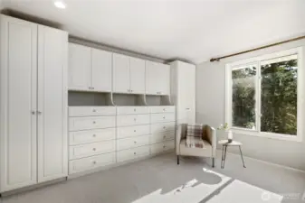 Expansive custom walk-in closet with an abundance of built-in shelves and storage with picturesque windows bringing in natural light.
