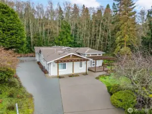 Bird’s-eye view reveals the home's cul-de-sac location, ample driveway parking, and private wooded backdrop.