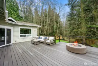 Expansive low-maintenance composite deck creates the perfect outdoor living space, complete with modern fire feature and peaceful views of the surrounding trees.