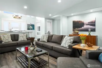 Comfortable and inviting main living room with spacious seating, updated flooring, and soft natural light flowing from the entry and surrounding windows.