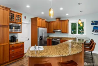 Large granite island with breakfast bar seating, perfect for casual dining, morning coffee, or gathering with friends.