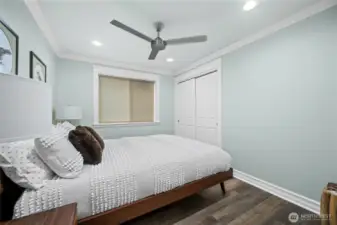 Comfortable guest bedroom with large window, ceiling fan, and closet storage.