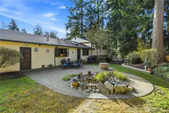 Beautiful backyard retreat featuring a patio and gathering space surrounded by mature trees.