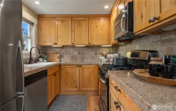 Gas cooking with an overhead microwave as well as granite counters and a tile backsplash.