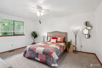 Spacious master bedroom has a ceiling fan and a window looking into the backyard.