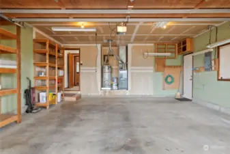 Spacious garage with built-in shelving, multiple shop lights and a suction fan. The exterior door leads to the sideyard.