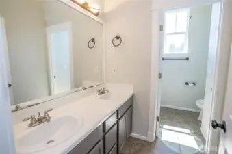 This upper-level full bath offers dual sinks and a private water closet with a shower/tub combo and toilet—perfect for guests or shared living.