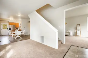 Sitting area adjacent to stairs, leads to dining space and kitchen.