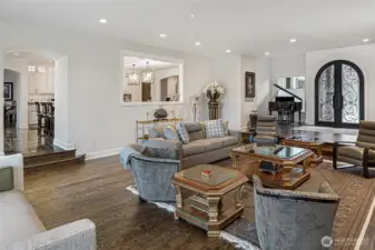 Elegant formal living room with hardwood floors, raised hearth, custom iron double doors, and seamless flow to adjacent entertaining spaces.
