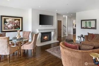 Open-concept living and dining area featuring hardwood flooring, elegant fireplace surround, recessed lighting, and seamless access to outdoor entertaining spaces.