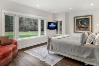 Light-filled bedroom with large picture windows overlooking manicured lawns and private acreage, offering serene views and natural light throughout.