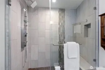 A gorgeous tiled shower and bench seating is a part of the primary bath.
