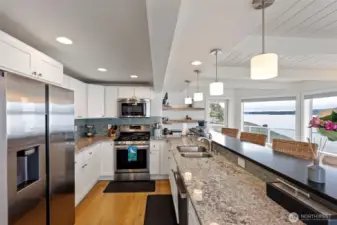 The functional kitchen has been upgraded with white cabinetry, granite counter tops, quartz eating bar, SS appliances, including a gas cooktop, and can lighting.