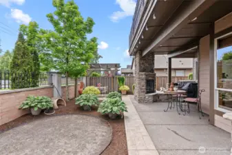 Stone detail surrounds the outdoor fireplace; outdoor kitchen includes built-in grill and prep counter located just off breakfast nook.