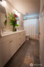 Main Bathroom. Beautifully designed primary bathroom blends comfort and style with a clean, modern aesthetic. Featuring a spacious dual-sink vanity, solid-surface countertops, and sleek fixtures, the space offers both function and elegance. A large framed mirror and contemporary lighting create a bright, inviting atmosphere.