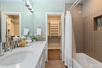 Tiled bath has a dual headed shower.