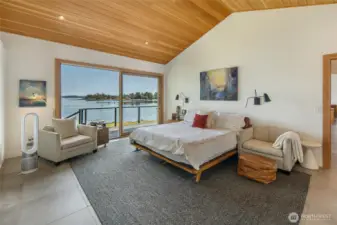 The primary bedroom with sliding doors to the deck. Wake up to serene views.