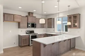 Kitchen features Shadow-stained Maple Shaker-style cabinets with quartz countertops and full tile backsplash and extended eating bar.