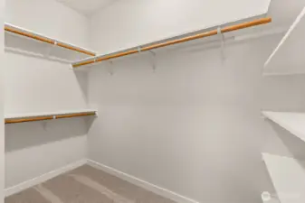 Primary walk-in closet boasts of hanging space and solid wood shelving.