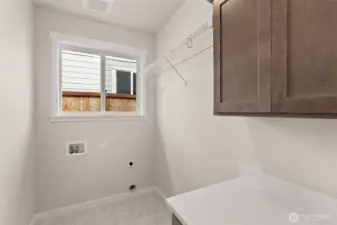 Separate laundry room with cabinets and a high hanging shelf for extended storage.