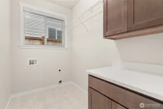 Separate laundry room with cabinets and a high hanging shelf for extended storage.