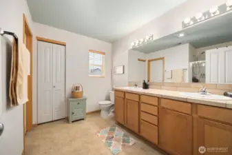 Looking across the primary bath with the linen storage closet beyond the dual sink vanity.