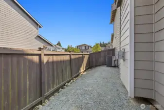 View of graveled fully fenced side yard on the garage side ofthe house. A/C location as well.