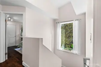 Across the hall from the primary bedroom, you'll find the other two bedrooms. A large picture window lets light into the stairs and hallway.