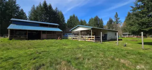 View of the open end of the shop, and into the run-in portion of the barn from inside the fenced pasture.(additional boards for fencing will be left, if unable to finish prior to sale. Currently has hot wire)