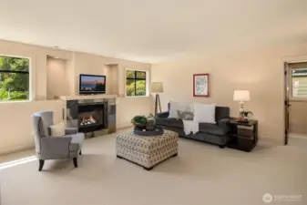 Main floor bonus room features the 1st of the 3 gas fireplaces in the home, as well as beautiful southern facing windows, framing the views of fully landscaped side garden. Door to the right leads to full bathroom, wet bar, and storage/office space area to the right.