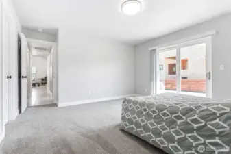 Primary bedroom has sliding glass door to a small patio and the back yard.