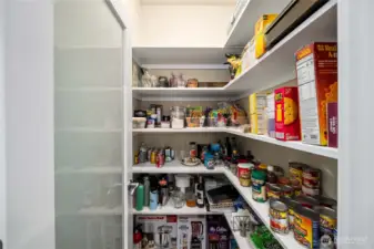 Spacious walk-in pantry with custom shelving provides exceptional storage and organization.