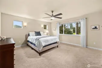 Serene primary suite accessed through elegant French doors, featuring plush carpet, stylish wall sconces, and beautiful golf course views.