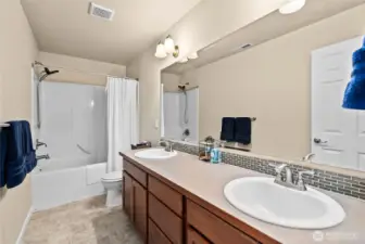 Full guest bathroom featuring a large dual vanity, generous counter & storage space, and a tub/shower combination.