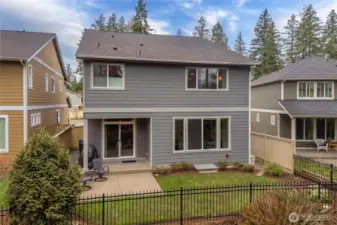 Rear view of the home showcasing the patio, easy-care yard, and tranquil natural setting.