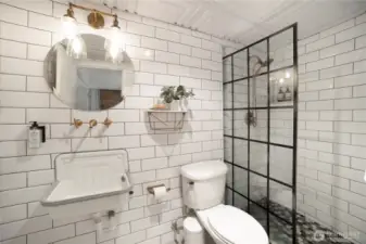 Newer renovations. Bathroom with wall to wall subway tile with marble accents, wall hung fixtures, newer light fixtures, shower with marble niche