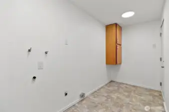 Utility area with hookups and extra storage potential. Door to garage is across from cabinet.