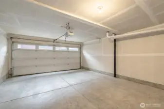 Two car garage with space for storage. Please note we have digitally enhanced this image removing some items in garage. There is a damaged door panel in process of being repaired.