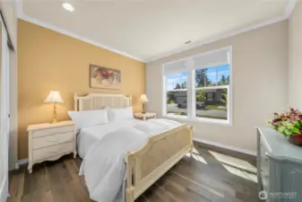 Guest bedroom w/ Engineered flooring, crown molding and lots of natural light and window coverings.