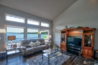 cozy living space with panoramic water views, vaulted ceilings and natural light pouring through picture-perfect windows