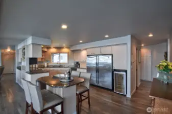 sleek gourmet kitchen with stainless steel appliances, granite counters, wine fridge and inviting island perfect for entertaining