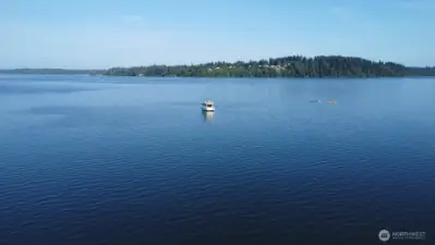 peaceful Totten Inlet views with calm blue waters, moored boat and forested shoreline- nature's beauty in every direction