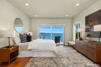 An expansive primary suite with private deck and serene water views. Pocket doors enclose the hallways to the primary bedroom wing.